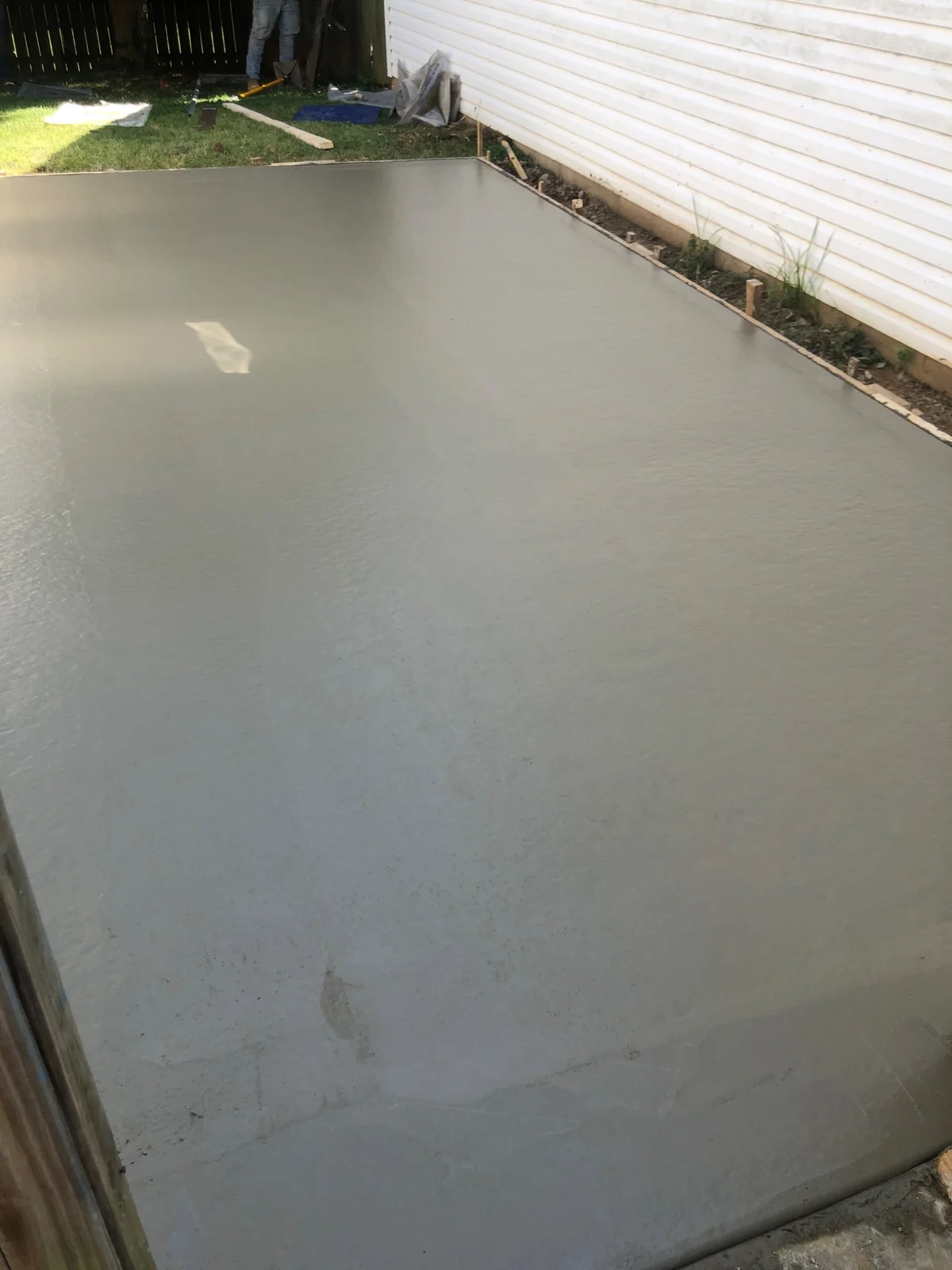 Concrete slab within formwork beside a house with white siding