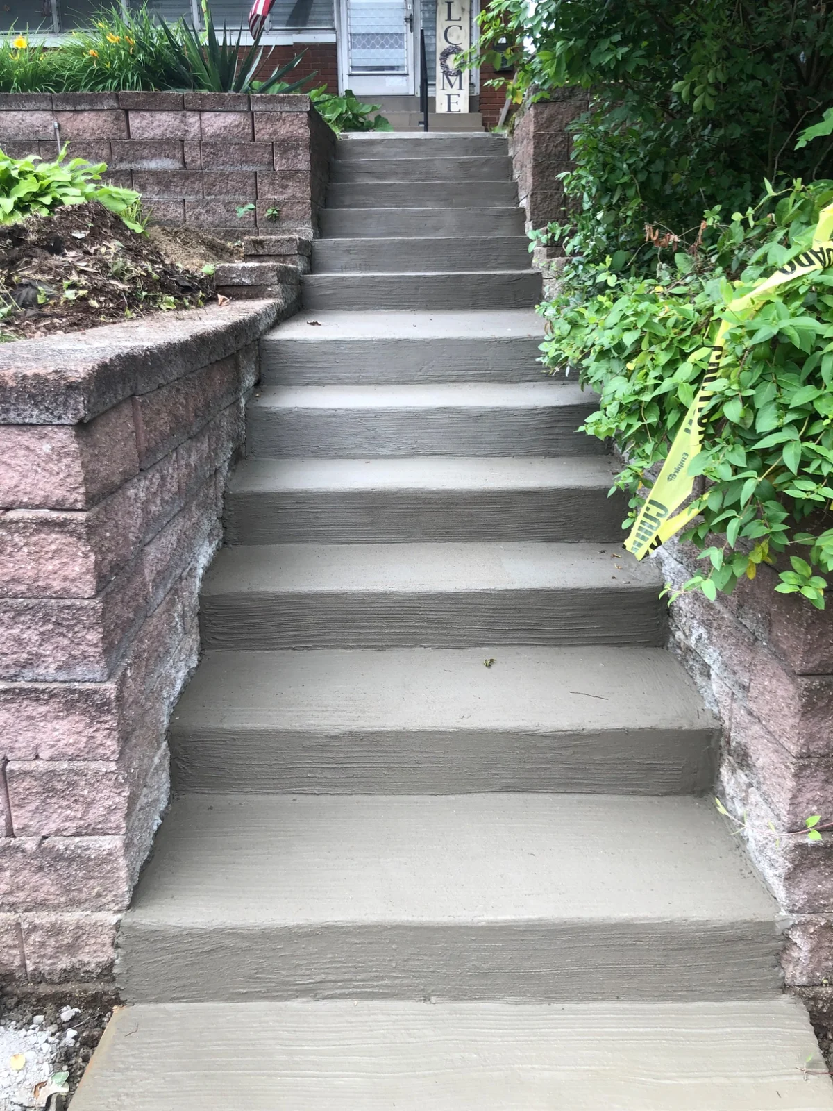 Concrete steps between block retaining walls leading to a home entrance